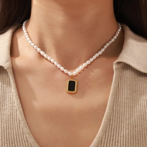 Elegant pearl necklace with black acrylic zircon pendant worn by a female model