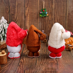 Three Christmas gnomes plush dolls in red and brown colors with rustic wooden background