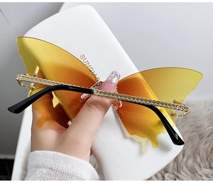 Detail of butterfly-shaped gradient yellow sunglasses with golden metal chain temples