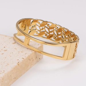 Detail showing vintage gold-plated hollow geometric bracelet on a textured stone surface