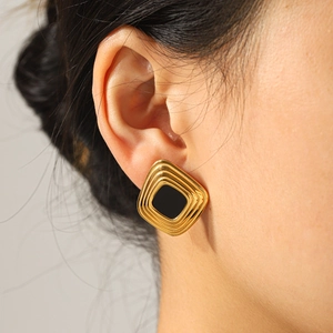 Vintage gold geometric square earrings with black enamel inlay worn by a model