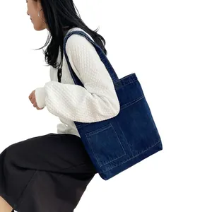 Detail of dark blue denim tote bag with white embroidery and side double pockets