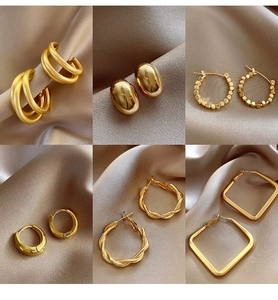 Variety of retro gold geometric hoop and stud earrings displayed on champagne silk fabric