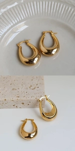 Detail of chunky gold teardrop hoop earrings with high polish finish on elegant background