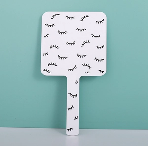 Detail of white square handheld makeup mirror with cute eyelash design and long handle