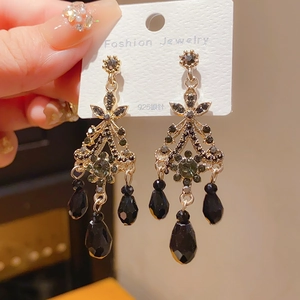 Macro detail of vintage dark style earrings with green crystals and black tassels