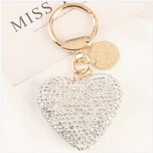 Detailed macro view of heart-shaped rhinestone keychain with gold ring and engraved tag