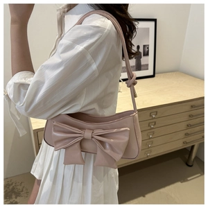 Detailed shot of pink crescent underarm bag with a large bow on a leather texture