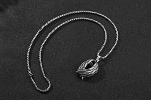 Détail macro du pendentif aile en acier rétro avec chaîne vénitienne sur fond texturé