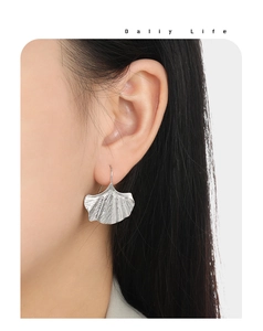Détail de boucles d'oreilles feuille de ginkgo argentées avec texture brossée