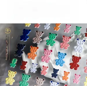 Macro shot of 5D embossed colorful teddy bear nail stickers with fine stitch texture