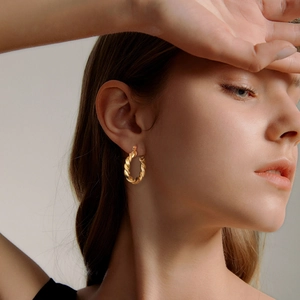 Close-up of model wearing 18K gold plated stainless steel twisted hoop earrings