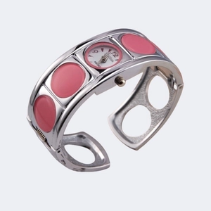 Detailed view of silver bangle watch with pink oval accents and white dial numeral 12
