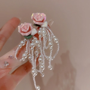 Detailed macro shot showing elegant pink rose earrings with white pearl beaded tassels