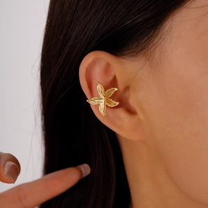 Detailed close-up of a golden starfish ear cuff with textured metallic finish on ear