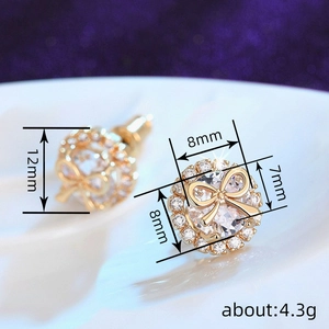 Macro detail of gold bow stud earrings with clear zircon stones and size dimensions