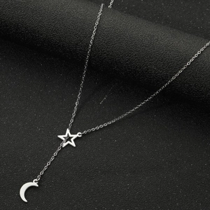Détail du collier argenté avec pendentifs étoile et croissant de lune polis