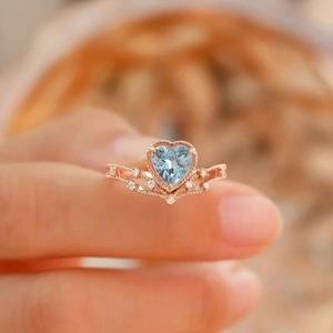 Rose gold heart-shaped light blue topaz ring with crown-style diamond accents