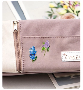 Detail view of blue and purple enamel lily of the valley brooches pinned on a fabric pouch