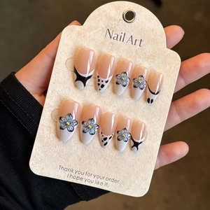 Détails de faux ongles French 3D à fleurs bleues et motifs vache sur carte beige
