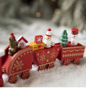 Close-up of red wooden Christmas train decor with bear and snowman on white snow base