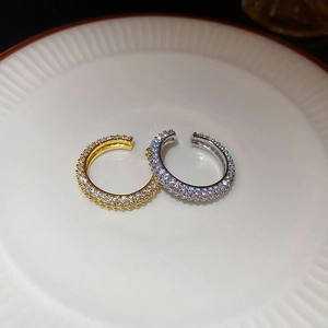 Macro shot of gold and silver pavé-set cubic zirconia ear cuffs on a white ceramic plate