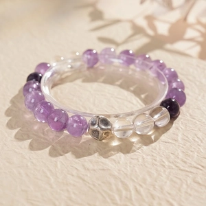 Macro shot of amethyst beads with a vintage silver pi xiu charm on a soft fabric base