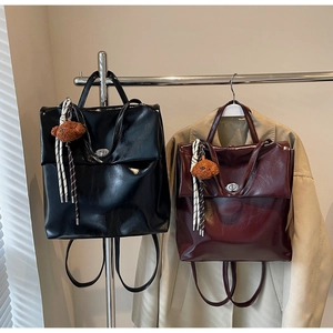 Detail of vintage faux leather backpacks in black and burgundy with bear charms