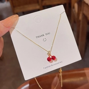 Vue détaillée du collier avec pendentif cerise rouge sur une chaîne dorée