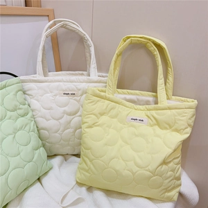Detailed view of flower-quilted padded tote bags in green, white, and yellow colors