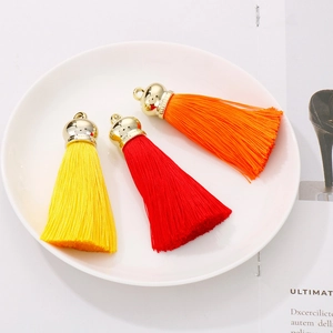 Three colorful cotton tassels in red, yellow and orange with golden stainless steel caps