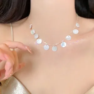 Close-up of minimalist silver chain necklace with white shell disc pendants on model