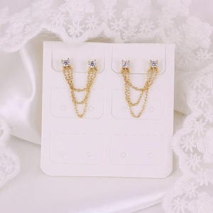 Detailed view of 925 silver golden tassel earrings with round cubic zirconia on white lace