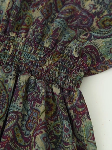 Close-up of smocking detail on metallic paisley chiffon dress with elastic gold threads