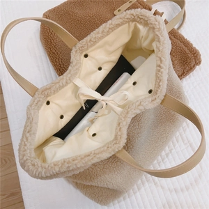 Detail view of lambswool tote bag showing magnetic snap, drawstring and fabric lining