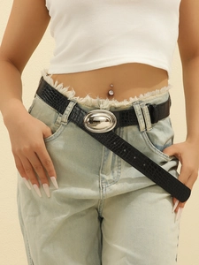 Close-up of black crocodile embossed leather belt with oval silver buckle on jeans