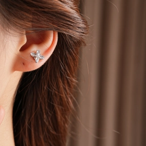 Gros plan d'une boucle d'oreille fleur à quatre pétales en zircon et argent poli
