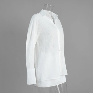 Detail showing the pleated texture and wide cuffs of the white long-sleeve blouse