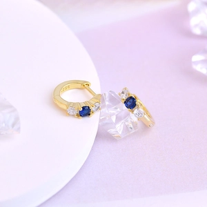 Detail of S925 sterling silver stamp on gold-plated huggie earring with blue zircon