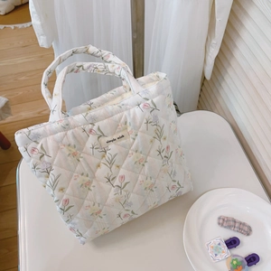 Detail of floral quilted cotton tote bag featuring rhombic texture and woven label