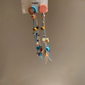 Close-up of Bohemian fish shell tassel earrings with colorful beads and ethnic woven design
