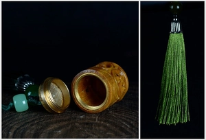 Macro shot of sandalwood sachet pendant with brass screw mouth and green silk tassel