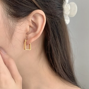 Detail of square geometric S925 sterling silver earring worn by a model in gold finish