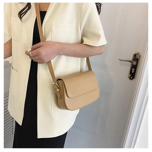 Detail of khaki leather crossbody bag with adjustable strap and sleek flap design