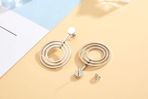 Detailed view of geometric triple-layered silver hoop earrings with butterfly backings
