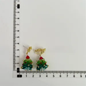 Close-up of handmade beaded Christmas tree earrings with size measurements on white background