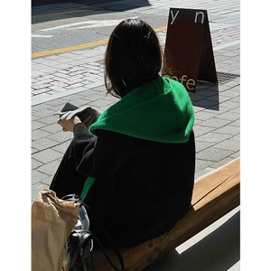 Winter set with green knit hooded scarf and black coat shown from back on street bench