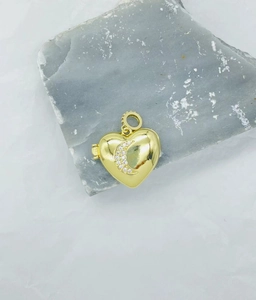 Detailed view of a golden heart locket with crescent moon cubic zirconia on a stone
