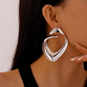 Close-up of model wearing exaggerated irregular geometric silver metal stud earrings