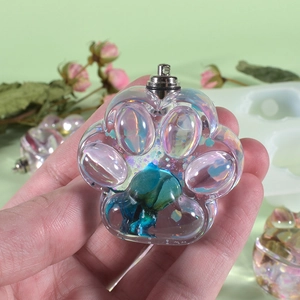 Close-up of a DIY resin cat paw pendant with blue dried flowers and metallic hanging loop